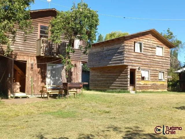 Vista exterior de las cabañas rústicas de madera de El Manzanito con jardín