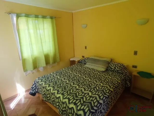 Dormitorio matrimonial con paredes amarillas y cortinas verdes