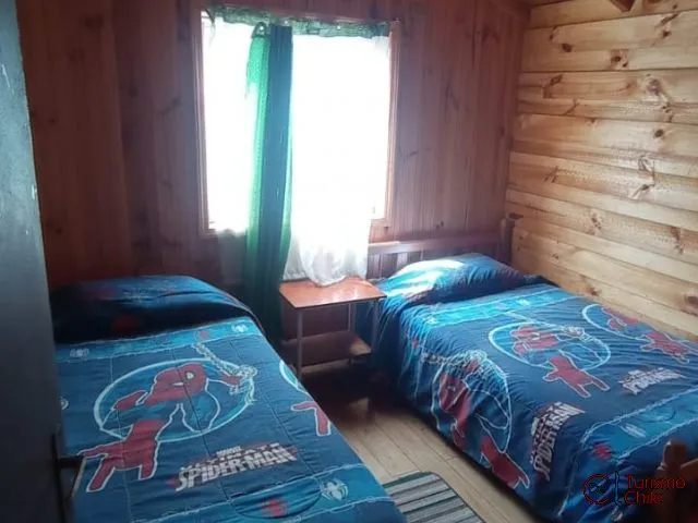 Dormitorio con dos camas individuales y paredes de madera nativa
