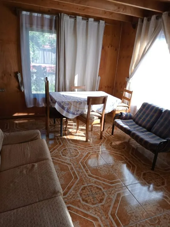 Comedor y living de cabaña con mesa, sillas y sofá en Cabañas La Ita