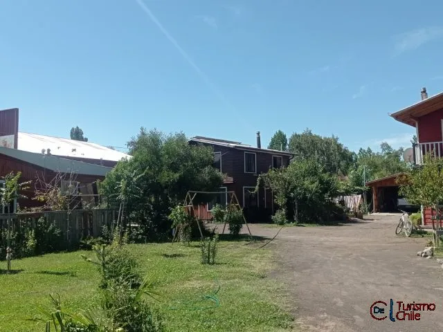 Área común con jardín, zona de juegos y cabañas de fondo en Cabañas La Ita