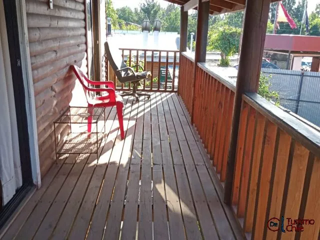 Terraza de madera con sillas y vista al jardín en Cabañas La Ita Salto del Laja
