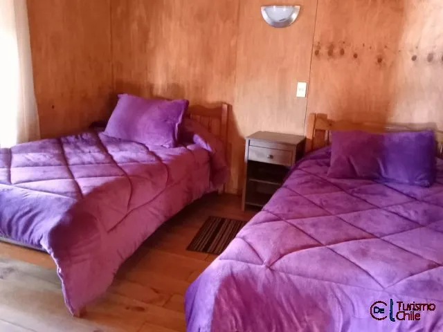 Segundo dormitorio con dos camas individuales y velador de madera