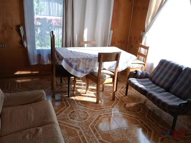 Comedor luminoso con mesa y sofá en interior de cabaña de madera