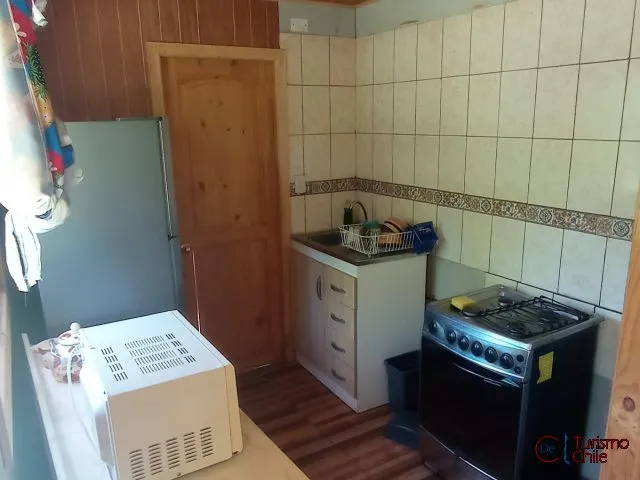 Cocina equipada con refrigerador, cocina a gas y mesón en cabaña Las Violetas