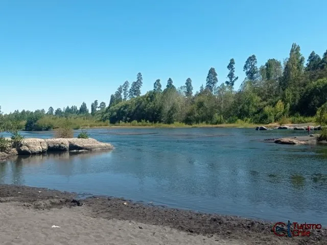 Playa de arena negra del río Laja con kayak y carpas en Camping Los Lagos